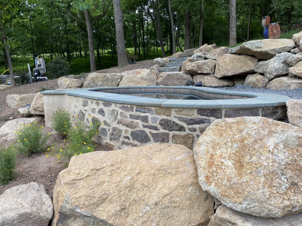 Custom outdoor living space with elevated spa and boulders