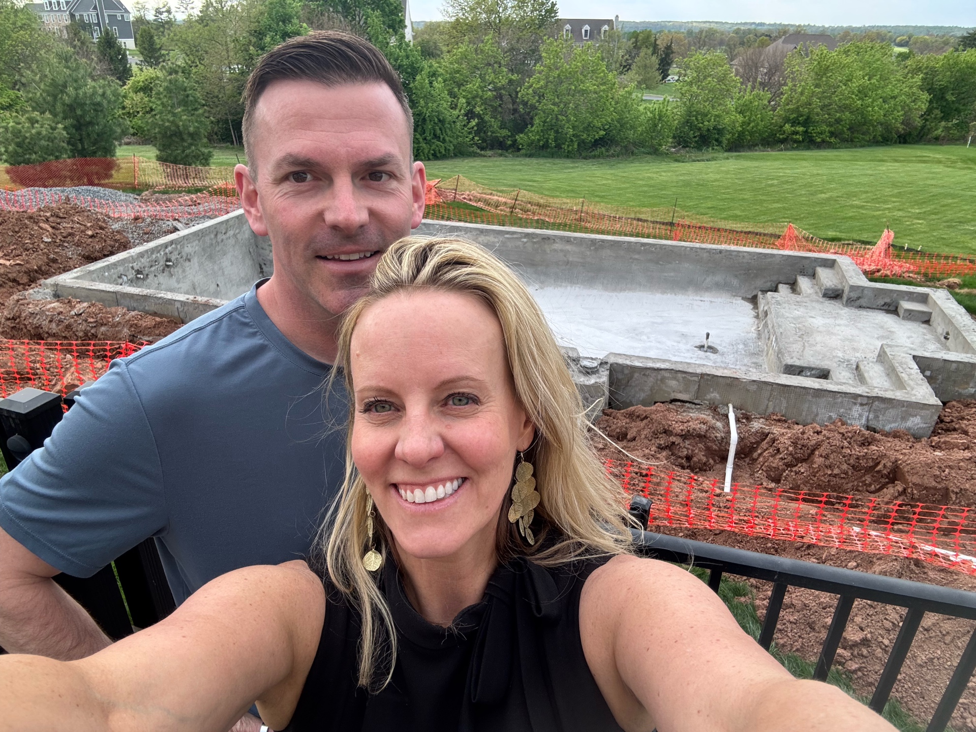 Happy clients taking a selfie in front of their gunite shell — the moment it becomes real