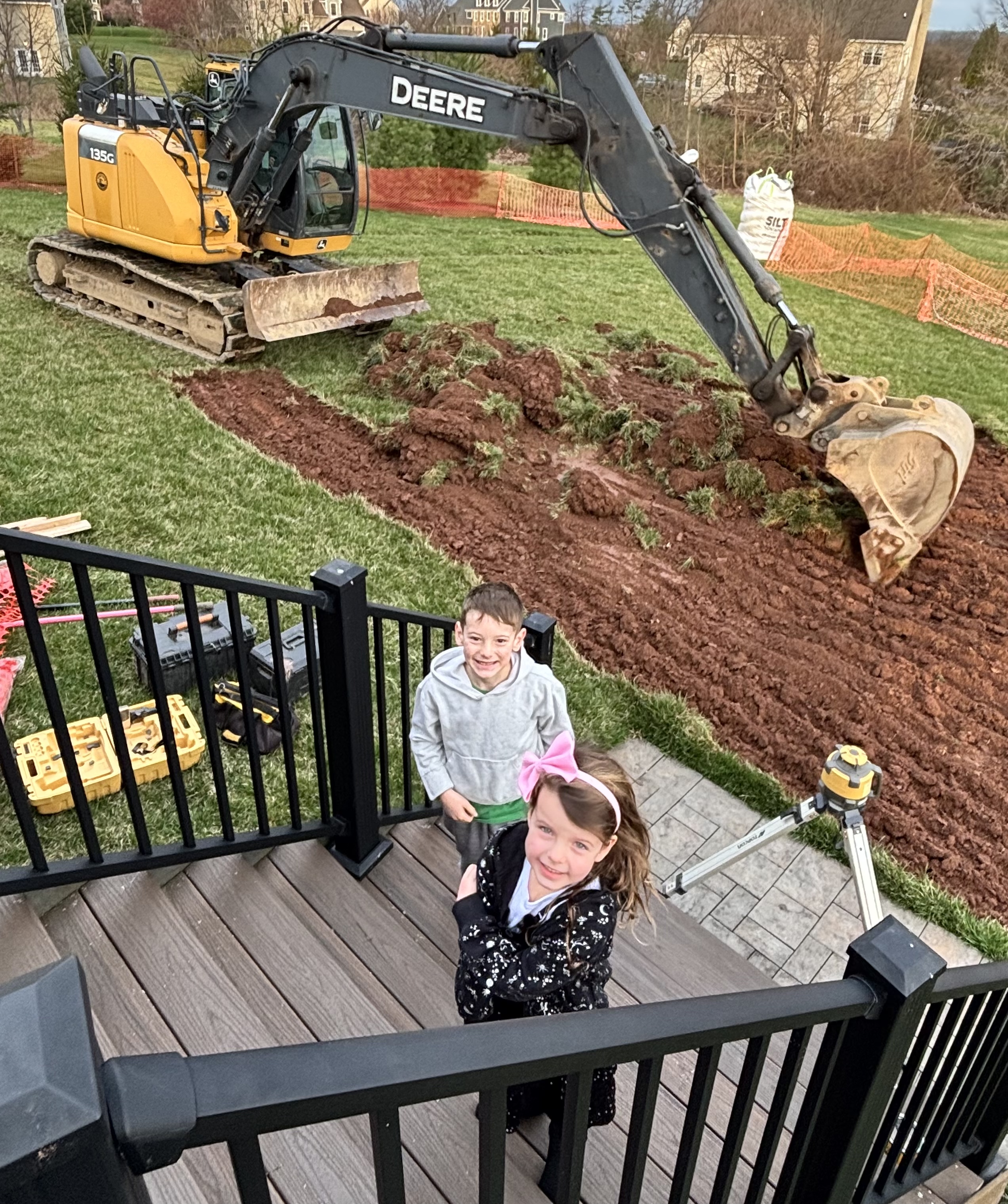 Excited kids watching the John Deere excavator on Day 1 of construction